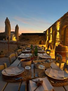 un lungo tavolo con piatti di cibo su una spiaggia di Masseria Specula a San Pietro in Bevagna