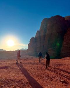 eine Gruppe von drei Personen, die in der Wüste spazieren gehen in der Unterkunft Wadi Rum Kenan Camp in Wadi Rum