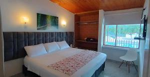 een slaapkamer met een groot bed en een raam bij El Cortijo Hotel Campestre in Santa Rosa de Cabal +48 foto's