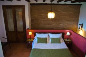 a bedroom with a bed with a red headboard and two lamps at Casa Núm 8 in Válor