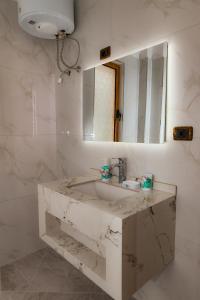 a white bathroom with a sink and a mirror at Eden Hotel in Shëngjin +29 photos