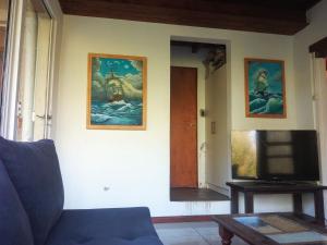 a living room with a blue couch and a tv at Casa del Bosque Sierra de los Padres in Sierra de los Padres
