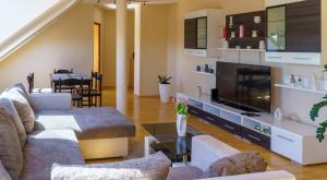 Una sala de estar con dos sofás y un televisor. en KLEO Apartman, en Pécs