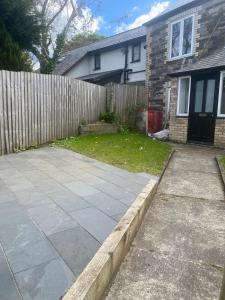 a backyard with a fence and a sidewalk at Hideaway Cottage in Camelford