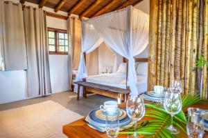 a bedroom with a bed and a table with wine glasses at Casa Rocha Trancoso in Trancoso