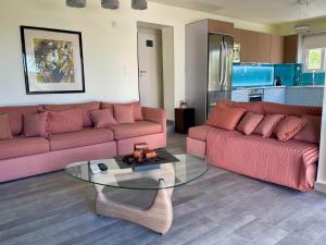 a living room with two pink couches and a glass table at Jolie apartment-Panorama view in Porto Rafti