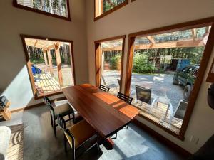 a dining room with a wooden table and windows at Jordan River Coastal Cottage in Shirley