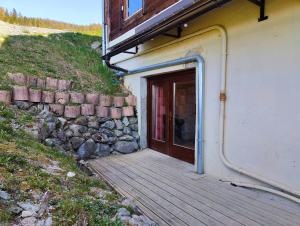 a building with a wooden door next to a stone wall at Petit Mont Blanc Guest House in Peisey-Nancroix
