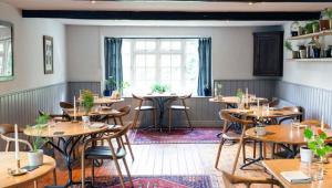 un restaurante con mesas y sillas de madera y una ventana en Hotel COSTAA LA CAGE Near Delhi Airport BY GROSS GROUP, en Nueva Delhi