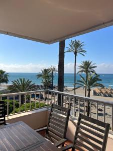Un balcón con mesa y sillas y la playa. en Las Palmas 2, en Marbella