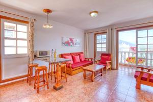 a living room with red chairs and a table at Apartamento Roque Horizonte in Puerto Naos +33 photos