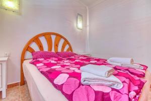 a bedroom with a bed with a pink blanket and pillows at Apartamento Roque Horizonte in Puerto Naos