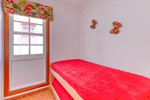 a bedroom with a red bed and a window at Apartamento Roque Horizonte in Puerto Naos