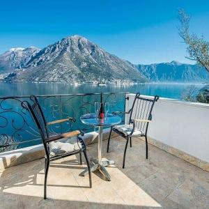 Duas cadeiras e uma mesa numa varanda com vista para um lago em Apartments Boka Vista em Kamenari