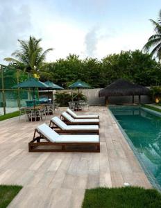 a group of lounge chairs next to a swimming pool at Casa Aroeira Milagres in São Miguel dos Milagres