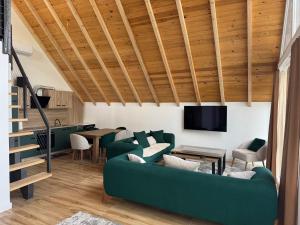 a living room with a green couch and wooden ceilings at Villa Dielli Gadish in Gnjilane