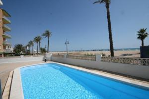 una piscina junto a una playa con palmeras en Apartamentos Barramundi, en Peñíscola