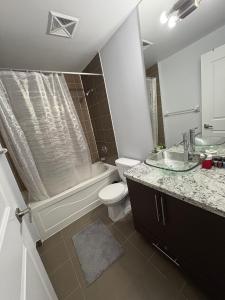 a bathroom with a toilet and a tub and a sink at Cozy Ensuite private room homestay in Mississauga