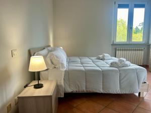 a bedroom with a bed with a lamp and a window at Serravalle Outlet Prime Apartments in Serravalle Scrivia