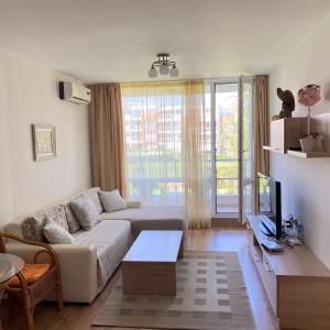 a living room with a couch and a tv at Тристаен апартамент в затворен комплекс in Chernomorets