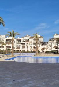 a large building with palm trees and a swimming pool at Ground floor family apartment, Close to Town and pool in Casas del Cura