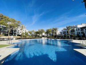 a large blue swimming pool with palm trees and buildings at Ground floor family apartment, Close to Town and pool in Casas del Cura +8 photos