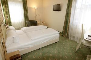 ein Hotelzimmer mit einem weißen Bett und einem TV in der Unterkunft Apart Hotel Deutschmeister in Bad Mergentheim