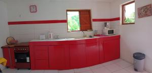 a red kitchen with a sink and a microwave at Divima in Sainte-Anne +1 photo