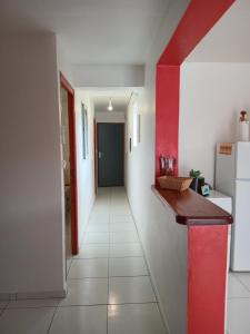a hallway of a kitchen with a red wall at Divima in Sainte-Anne
