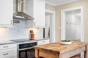 a kitchen with white cabinets and a wooden table at Luxurious Retreat in Historic Downtown Burlington Downstairs Only in Burlington +36 photos