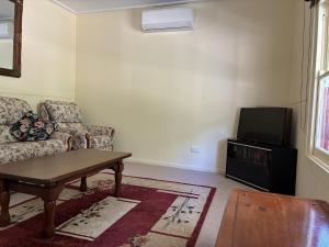 un salon avec un canapé et une télévision dans l'établissement School Cottage, à Walhalla