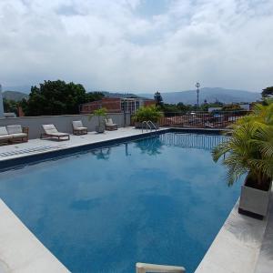una grande piscina blu con sedie a sdraio e alberi di Apartaestudio Moderno a Cali
