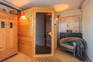 a sauna with a glass door and a chair in a room at 5 Sterne FeWo mit Garten und Bergblick in Chiemsee-Nähe in Übersee