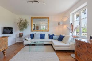 a living room with a white couch and a mirror at 5 Sterne FeWo mit Garten und Bergblick in Chiemsee-Nähe in Übersee