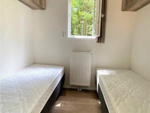 two beds in a room with a window and a radiator at Chalet in Valthe near Emmen Zoo in Beekbergen