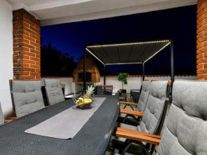 a dining table and chairs on a patio at night at Four Bedroom Villa With Hot Tub in Pašman