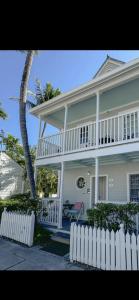 a white house with a white fence and a palm tree at Dee's Dream Sunset Condo - #151 in Key West