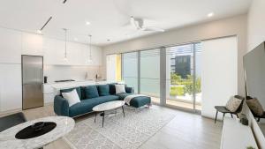a living room with a blue couch and a kitchen at Modern Luxury 2bed by 7 Mile Beach in Upper Land