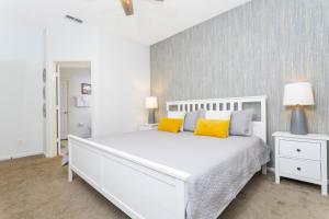 a white bedroom with a white bed with yellow pillows at Villa Helena, Windsor Palms in Kissimmee