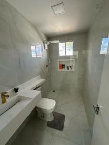 a white bathroom with a toilet and a sink at Casa com piscina e área gourmet para o São João in Campina Grande
