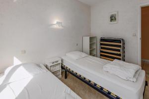 two beds in a small room with white walls at Epsom 0402 in Sint-Idesbald