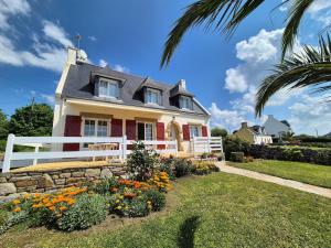 a house with a white fence and some flowers at Holiday Home in Plouhinec with Sea Views in Plouhinec