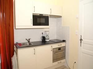 une petite cuisine avec des armoires blanches et un évier dans l'établissement Cycling Escape in Montbrun, à Montbrun-les-Bains