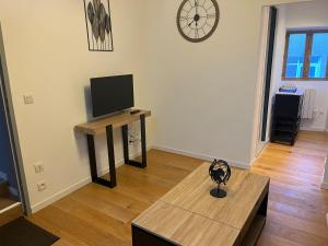a living room with a table and a tv on a wall at Studio central et chaleureux in Belley