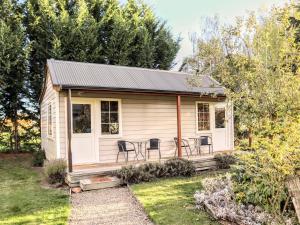 a tiny house with a porch and chairs at Lauder School Bed & Breakfast in Lauder