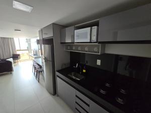 a kitchen with a black counter top and a microwave at Unity, Cabo Branco Flat 324 in João Pessoa