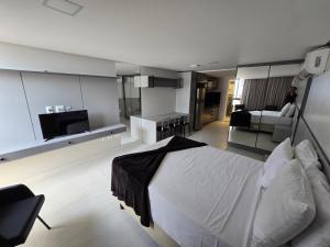 a bedroom with a large bed and a living room at Unity, Cabo Branco Flat 324 in João Pessoa