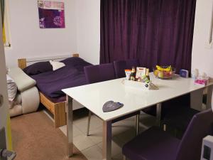 a room with a table and purple chairs and a bed at Doppelzimmer direkt vorm Emmental in Eriswil