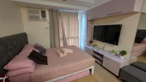 宿务Cozy Studio Apartment at Cebu IT Park的一间带床和平板电视的卧室
