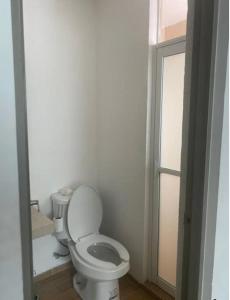 a white bathroom with a toilet and a window at Departamento terraza hulu in Guanajuato